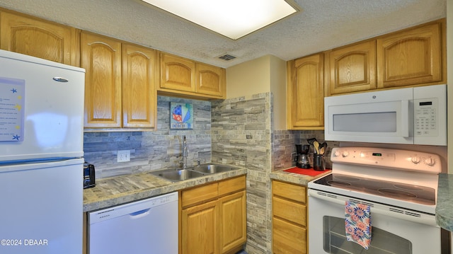 kitchen featuring a textured ceiling, sink, white appliances, and backsplash