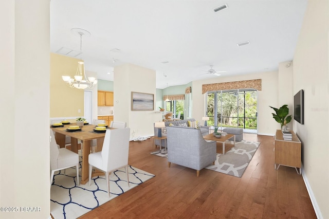 living room with ceiling fan with notable chandelier and dark hardwood / wood-style floors