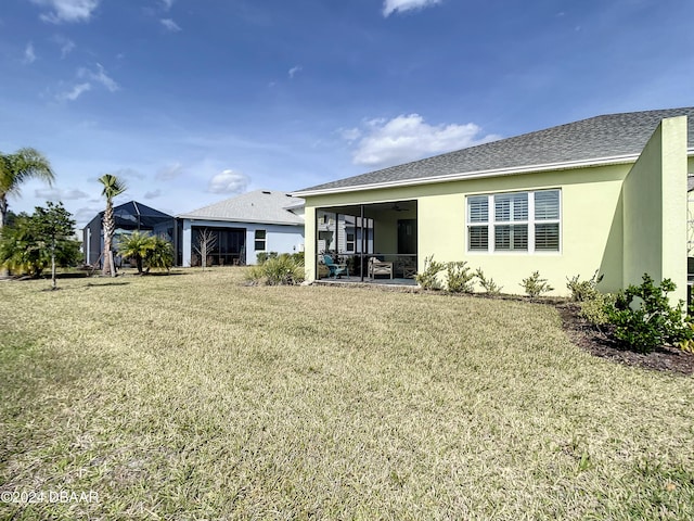 rear view of property featuring a lawn, a sunroom, and ceiling fan