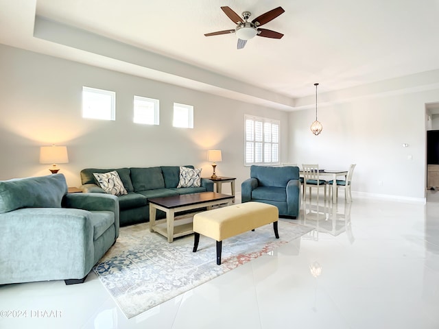 living room with a tray ceiling and ceiling fan