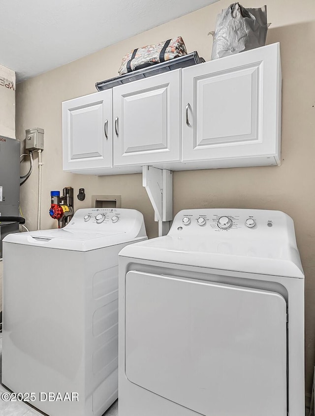 clothes washing area with cabinets and washing machine and dryer