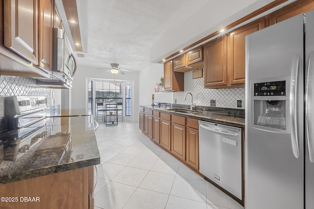 kitchen featuring dark stone countertops, sink, stainless steel appliances, and light tile patterned flooring