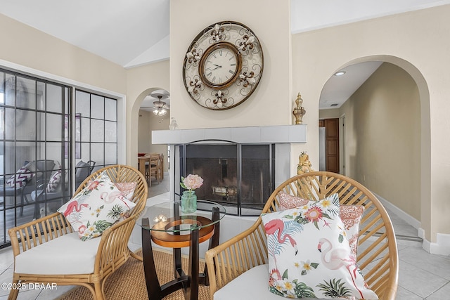 sitting room featuring ceiling fan, high vaulted ceiling, light tile patterned flooring, and a fireplace