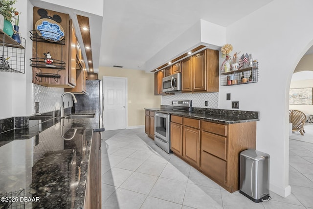 kitchen featuring tasteful backsplash, appliances with stainless steel finishes, sink, and dark stone countertops