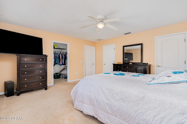 bedroom featuring a walk in closet, visible vents, baseboards, and light colored carpet