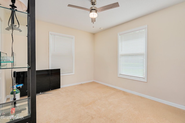 interior space with carpet floors, baseboards, and ceiling fan