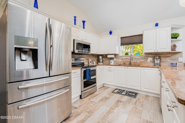 kitchen with a sink, vaulted ceiling, white cabinetry, open shelves, and appliances with stainless steel finishes
