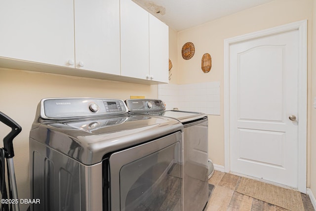 laundry room with cabinet space, light wood-style flooring, and separate washer and dryer