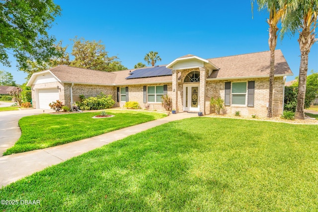 single story home featuring brick siding, solar panels, driveway, and a front lawn