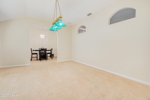 interior space with vaulted ceiling, arched walkways, an inviting chandelier, baseboards, and visible vents