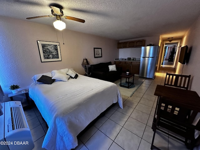 3501 S Atlantic Ave E Unit G20, Daytona Beach Shores, FL 32118 - bedroom featuring freestanding refrigerator, light tile patterned floors, a textured ceiling, ceiling fan, and a textured wall