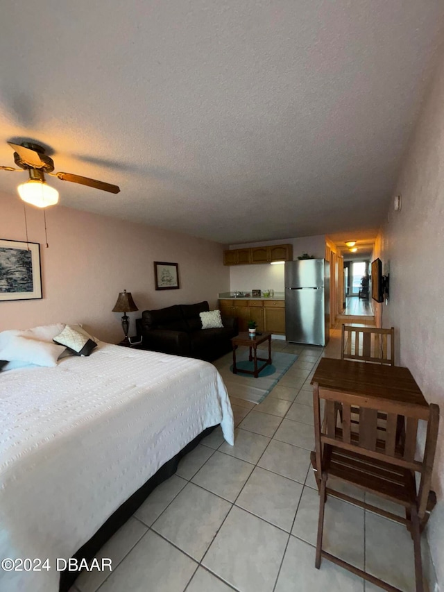 tiled bedroom featuring stainless steel refrigerator, ceiling fan, and a textured ceiling