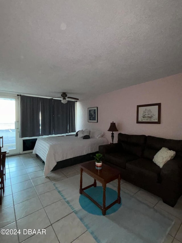 bedroom with access to exterior, light tile patterned flooring, and a textured ceiling