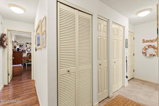 corridor featuring a textured ceiling and light tile patterned floors