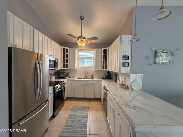 415 Jessamine Ave, New Smyrna Beach, FL 32169 - kitchen with appliances with stainless steel finishes, a sink, decorative backsplash, vaulted ceiling, and light stone counters