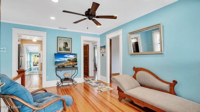 living area with hardwood / wood-style flooring, crown molding, and ceiling fan