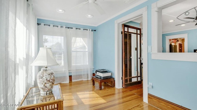 sitting room with crown molding, wood-type flooring, and ceiling fan