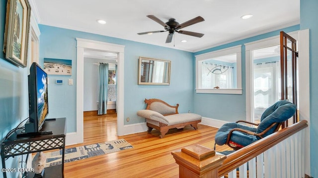 living area with ceiling fan, ornamental molding, and wood-type flooring