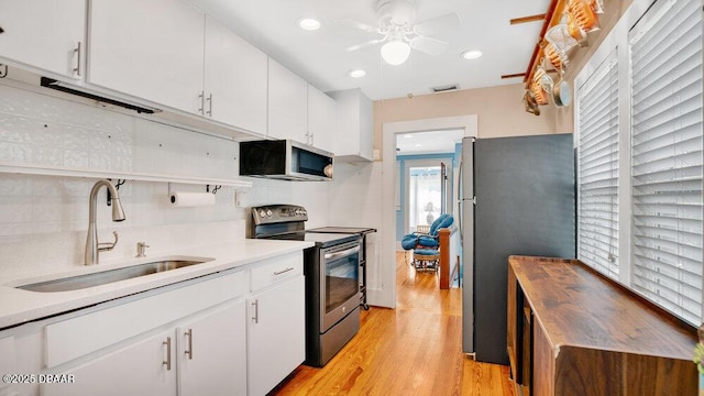 kitchen with sink, white cabinetry, stainless steel appliances, tasteful backsplash, and light hardwood / wood-style floors