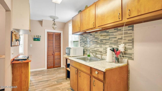 kitchen with tasteful backsplash, light hardwood / wood-style floors, sink, and a wealth of natural light