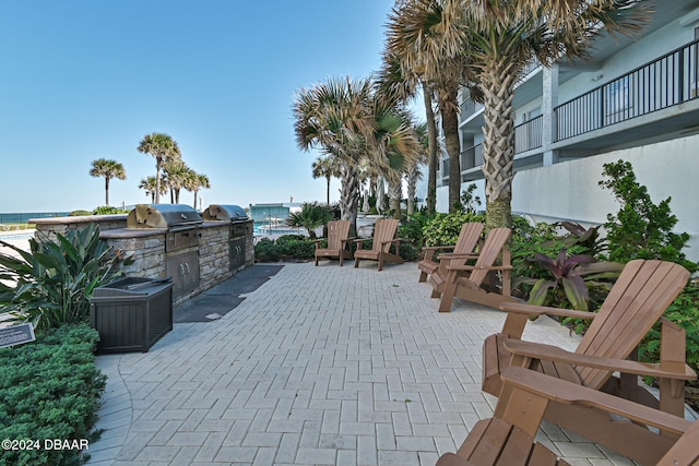 view of patio with a water view, exterior kitchen, a grill, and a balcony