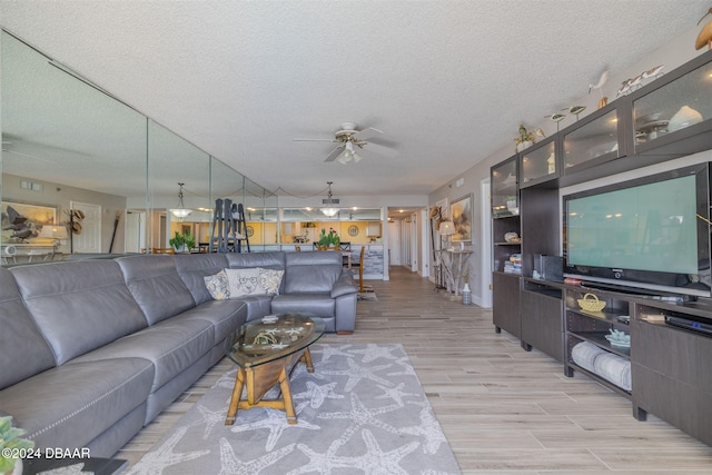 living room featuring light hardwood / wood-style flooring, a textured ceiling, and ceiling fan