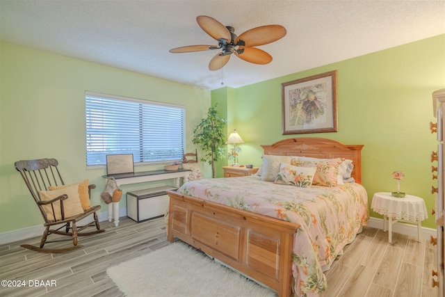 bedroom with ceiling fan, a textured ceiling, and light hardwood / wood-style floors