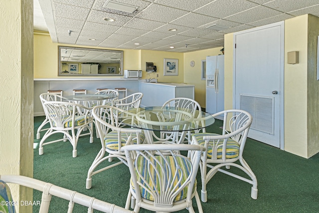 carpeted dining room with a drop ceiling