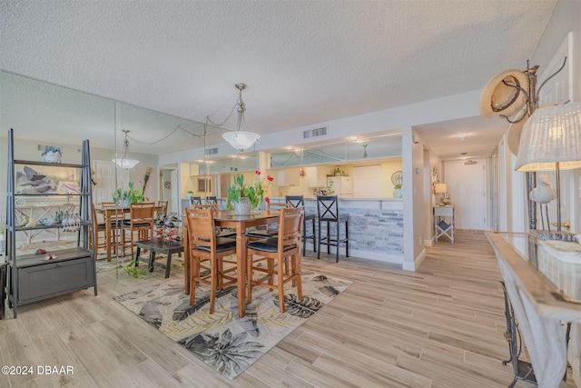 dining space featuring light hardwood / wood-style floors and a textured ceiling