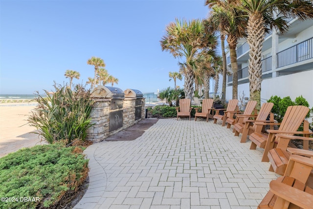 view of patio / terrace featuring a beach view, a water view, and exterior kitchen