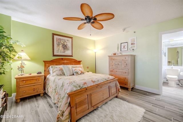 bedroom with ensuite bathroom, ceiling fan, a textured ceiling, and light hardwood / wood-style floors