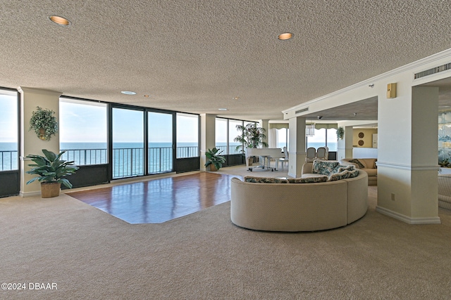 unfurnished living room with expansive windows, a water view, carpet floors, a textured ceiling, and ornamental molding