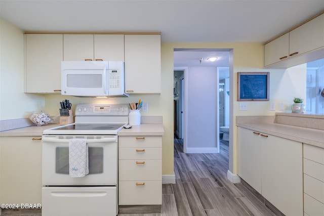 kitchen with white appliances, light hardwood / wood-style floors, and white cabinets