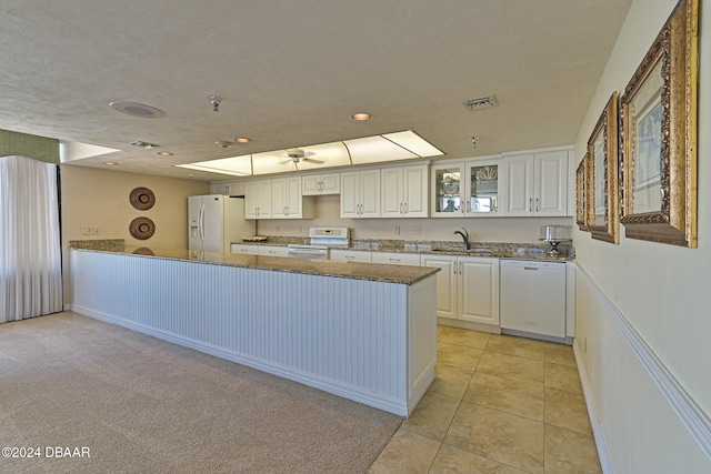 kitchen featuring white cabinetry, sink, light carpet, kitchen peninsula, and white appliances