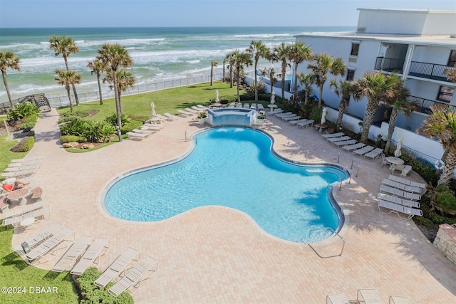 view of pool with a view of the beach, a water view, a yard, and a patio area