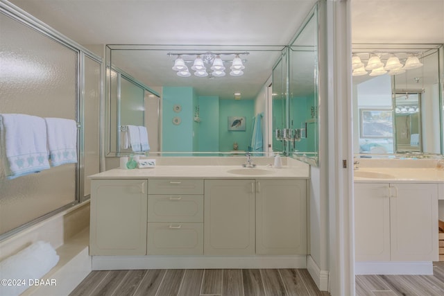 bathroom with enclosed tub / shower combo, wood-type flooring, and vanity