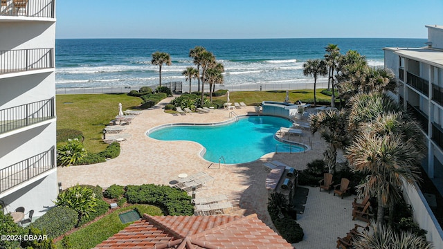 view of pool featuring a lawn, a beach view, a water view, and a patio area