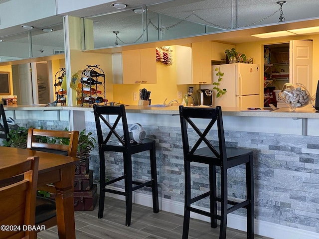 bar with hardwood / wood-style floors and white fridge