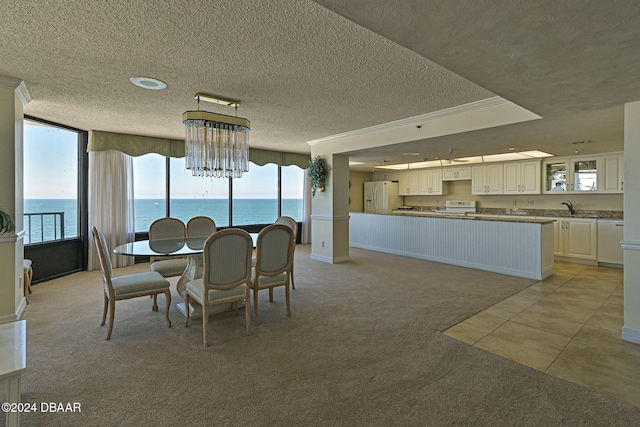 carpeted dining room featuring a water view, a textured ceiling, and sink