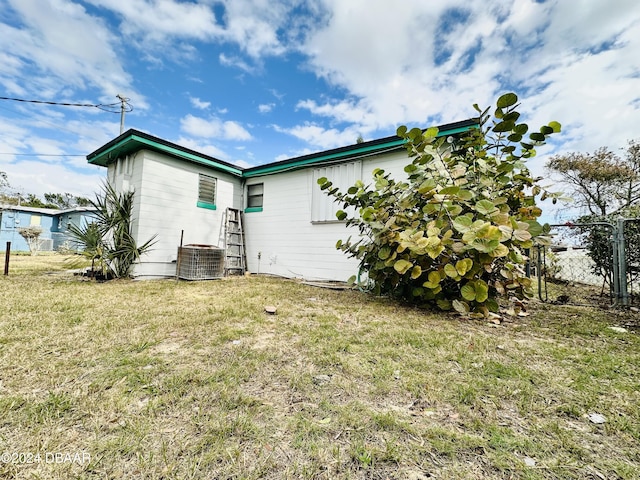 rear view of house featuring central AC and a lawn