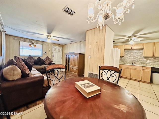 dining area featuring wooden walls, sink, light tile patterned flooring, and an inviting chandelier