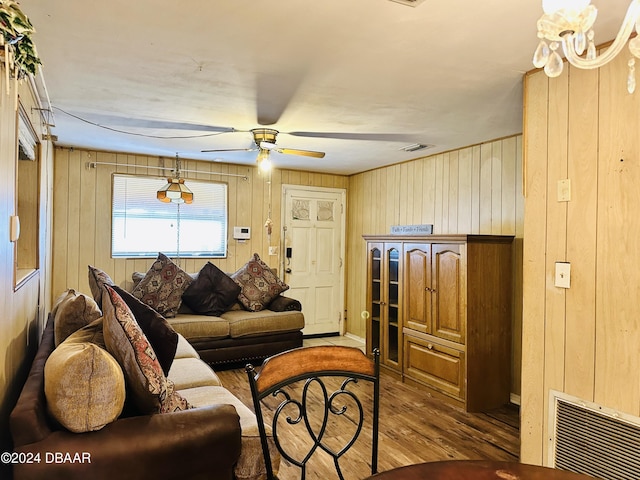 living room with hardwood / wood-style floors, ceiling fan, and wood walls