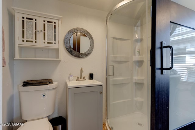 bathroom with vanity, a shower with door, and toilet