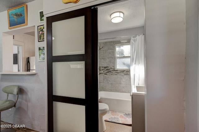 bathroom with shower / bathtub combination with curtain, a textured ceiling, and toilet