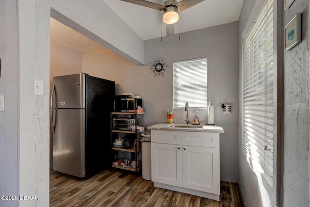 kitchen featuring sink, appliances with stainless steel finishes, white cabinetry, hardwood / wood-style floors, and light stone countertops