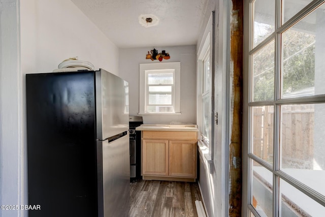 kitchen featuring stainless steel refrigerator, light brown cabinetry, and dark wood-type flooring