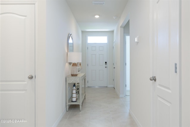 hall with light tile patterned floors, baseboards, and visible vents