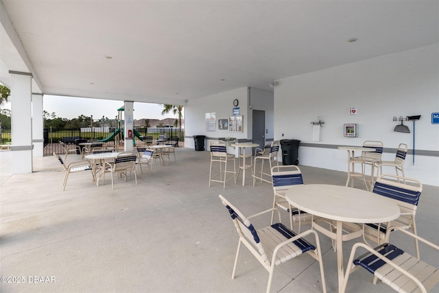 view of patio / terrace with playground community, outdoor dining area, and fence