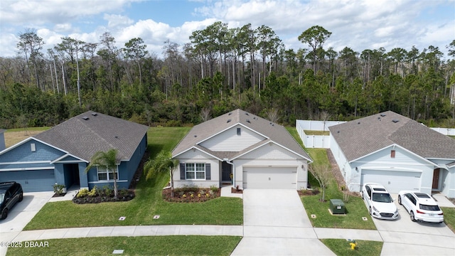 ranch-style house featuring concrete driveway, a forest view, and a front yard