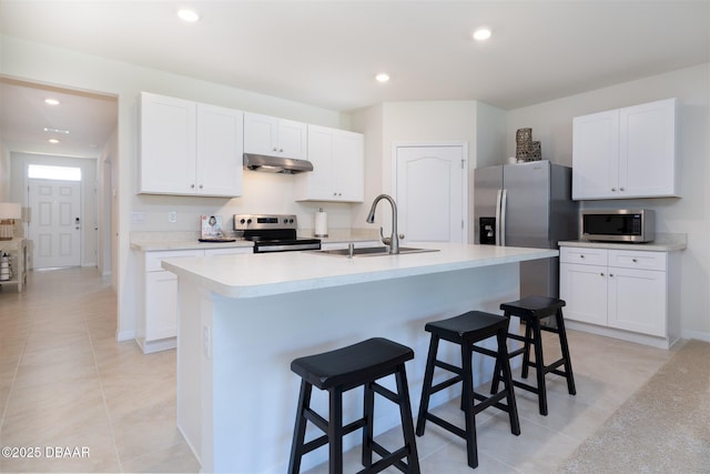 kitchen featuring under cabinet range hood, a sink, white cabinetry, light countertops, and appliances with stainless steel finishes